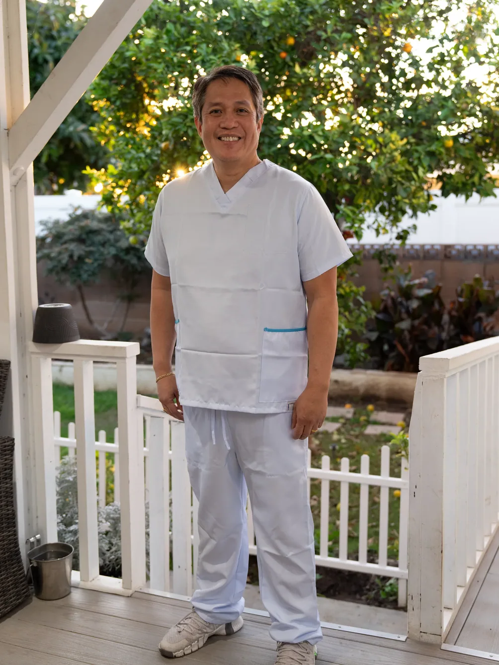 Smiling healthcare provider in white medical uniform standing on facility porch